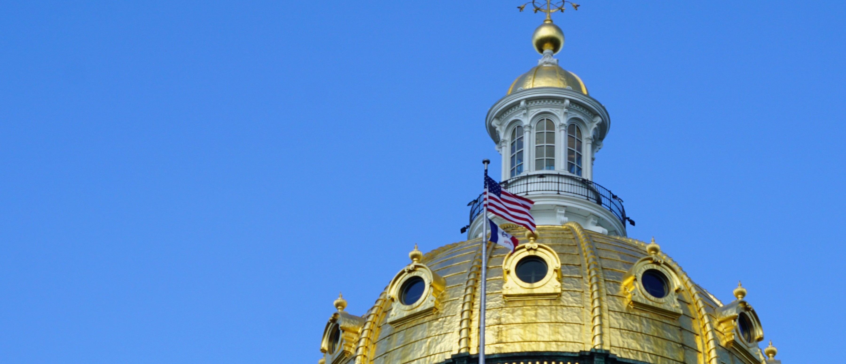 The Iowa State Capitol's gold dome against a clear sky.
